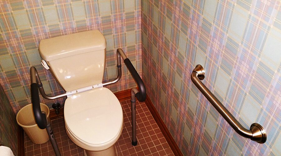 Toilet grab bars installed on tiled bathroom walls and floors.